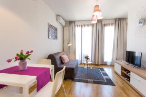布达佩斯Colours Apartments Deluxe with FREE Parking的客厅配有桌子、沙发和电视。