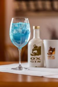 赫斯巴赫Hotel & Restaurant Zum Ochsen -Ox Distillery的酒杯里的蓝色饮料,酒瓶旁边