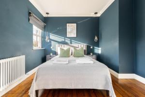 伦敦The Putney Villa的蓝色卧室配有一张带绿色枕头的大床