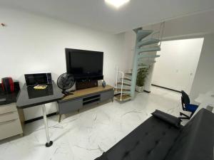 约恩维利Loft no Espinheiros - Joinville/SC的一间配有平面电视的客厅和楼梯