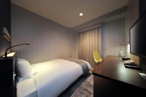 福岛JR-East Hotel Mets Fukushima的一间酒店客房,配有一张白色的床和一张书桌