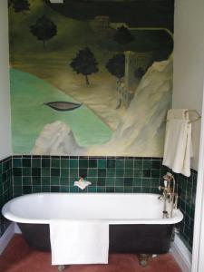 奥斯顿菲尔德斯丹斯霍普馆酒店的带浴缸的浴室,配有高尔夫壁画