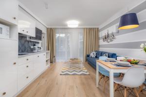 波别罗沃Pobierowo Beach Baltic Apartments by Renters的厨房以及带蓝色沙发和桌子的客厅。