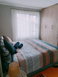 塞昆达Reutlwane Gardens Guesthouse的一间卧室配有一张带毯子的床和窗户