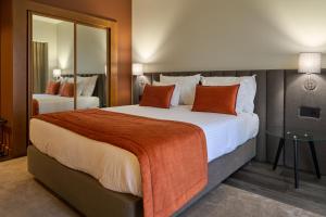 瓜尔达Hotel Versatile的酒店客房配有一张带橙色枕头的大床