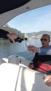 波尔图Sunset River - Douro的把一杯酒倒在船上的人