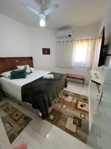 布罗塔斯Vila Pepira ViP的一间卧室配有一张床、一台电视和一张地毯。