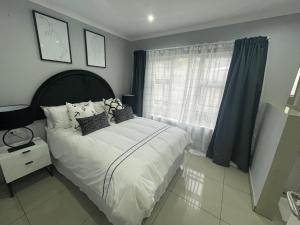 乌姆塔塔Trendy, Comfortable 1 bedroom Apartments in Mthatha的一间卧室配有带白色床单和枕头的床。