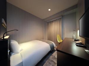 福岛JR-East Hotel Mets Fukushima的一间卧室配有一张床、一张书桌和一台电视