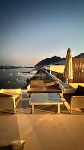 富查伊拉Luxury Villa 5 bedrooms with sea view and free boat的一组桌子和椅子,紧靠着水体