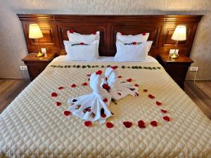 拉姆尼库沃尔恰索菲亚努大酒店的一张带两个婚礼毛巾和红玫瑰的床