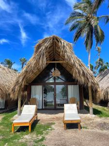 穆库拉岛Hotel Isla Mucura的一个带两把椅子和一个草屋的度假胜地