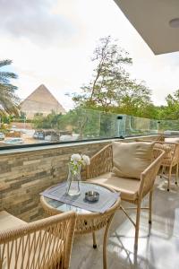 开罗Lotus Inn的庭院配有椅子和桌子,后面是金字塔
