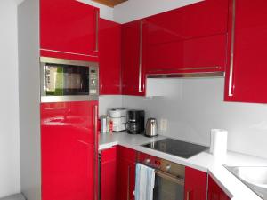 AmougiesGite de la Rhosnes的红色的厨房,配有白色的柜台和红色的橱柜