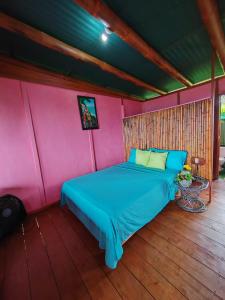SierpeFinca La Puesta del Sol - Miramar de Sierpe的卧室配有蓝色的床,位于粉红色的墙壁上