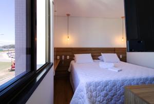 伊列乌斯Ilhéus Praia Hotel的一间卧室配有一张带白色床单的床和一扇窗户。