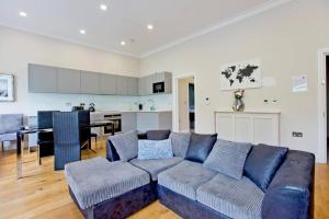 伦敦Stunning 1bed Kensington的一间带蓝色沙发的客厅和一间厨房