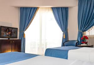 赫尔格达White Valley Palace的一间卧室设有两张床,窗户配有蓝色窗帘