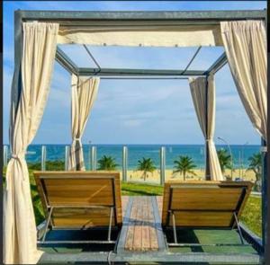 里约热内卢Hotel Nacional RJ - Vista Mar的两把长椅坐在凉亭下,俯瞰着海滩