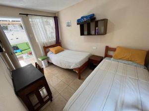 拉塞雷纳Hostal del Rosario La Serena的一间小卧室,配有两张床和窗户