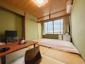 天草市Eimiya Ryokan - Vacation STAY 36252v的客房设有床、书桌和窗户。