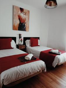 马德里Casa Cobo Exclusivo Alojamiento en Madrid的一间设有两张床的客房,墙上挂着一幅画