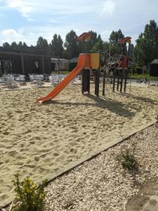 乌伊斯特勒昂RIVA BELLA MH 171的沙地里有一个红色滑梯的游乐场