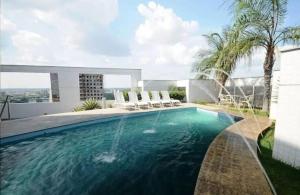 马瑙斯###SENSACIONAL### MERCURE APART HOTEL PREMIUM的一个带椅子的游泳池以及一座房子