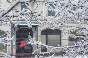 安锡钟楼阿纳西中心酒店 - 火车站的雪中用红伞行走的人
