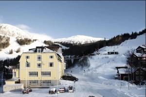 奥勒Are Alpine Retreat 6-Guest Ski Apt with Sauna的雪中一座黄色的大建筑,汽车停泊