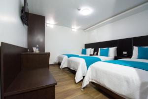 伊瓦拉维多利亚广场酒店的一间设有三张床的客房,配有蓝色和白色的床单