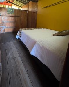巴亚索拉诺Posada Turística Rocas De Cabo Marzo的卧室铺有木地板,配有白色的床。