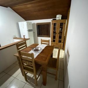 帕拉蒂Casa Beira Mar, Paraty-RJ的厨房配有木桌、椅子和冰箱。