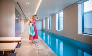 吉朗Holiday Inn & Suites Geelong, an IHG Hotel的身着连衣裙的女人站在游泳池旁