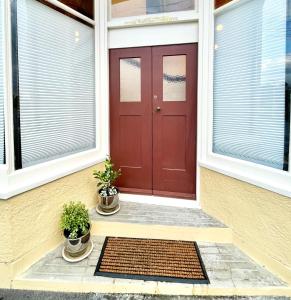 但尼丁Opoho Heritage Guest Suite的两盆植物房子上的红门