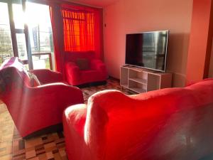 万卡约CASA HOSPEDAJE LAS MONTAÑAS的客厅配有红色家具和平面电视
