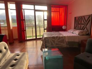 万卡约CASA HOSPEDAJE LAS MONTAÑAS的一间卧室配有红色窗帘、一张床和一张沙发
