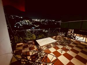 西姆拉The Aston Hills - A Luxury Stay , Shimla的夜间阳台上的桌椅