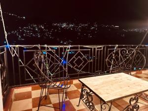 西姆拉The Aston Hills - A Luxury Stay , Shimla的夜间阳台上的桌椅