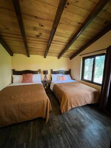 马萨米特拉Cabaña No.4 Puerta del Bosque Mazamitla.的客房设有两张床,配有木制天花板和木地板。