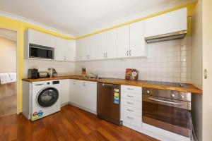 珀斯Swan River Applecross Heathcote Park 1BR Villa的厨房配有白色橱柜、洗衣机和烘干机