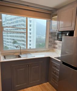 芭东海滩Patong Vacation Rentals - 28 SQM Studio Apartments - Located in the Heart of Patong with Kitchen, Private Bathroom, Seating Area, 65" Smart TV with Free WIFI的一个带水槽和大窗户的厨房