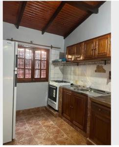 伊瓜苏港Parana house的厨房配有木制橱柜和白色冰箱。
