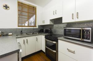 格拉夫顿格雷度假屋的厨房配有白色橱柜和微波炉