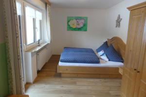 贝希特斯加登Ferienwohnungen Haus Kunterbunt的一间卧室配有一张带蓝色床单的床和一扇窗户。