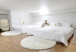 仁川市Loco House的一间卧室配有两张带白色床单和地毯的床。