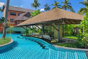 芭东海滩Courtyard by Marriott Phuket, Patong Beach Resort的茅草屋顶度假村的游泳池