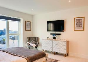 纽基34 Cliff Edge 2nd floor Newquay luxury sea-view residence的一间卧室配有一张床、一把椅子和电视。