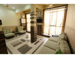 博尔本德尔Hotel Ronak Royal, Porbandar的带沙发、椅子和窗户的客厅
