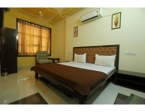 博尔本德尔Hotel Ronak Royal, Porbandar的一间卧室配有一张大床和一把椅子